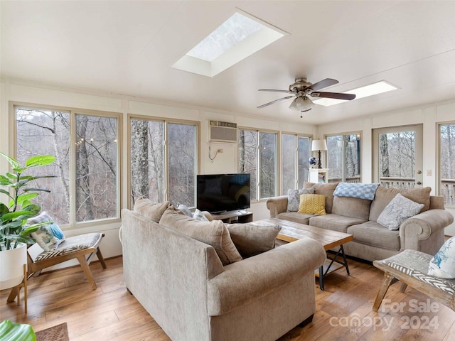 living room featuring ceiling fan, a healthy amount of sunlight, a wall unit AC, and a skylight