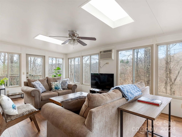 sunroom / solarium featuring a skylight, a wall unit AC, and ceiling fan