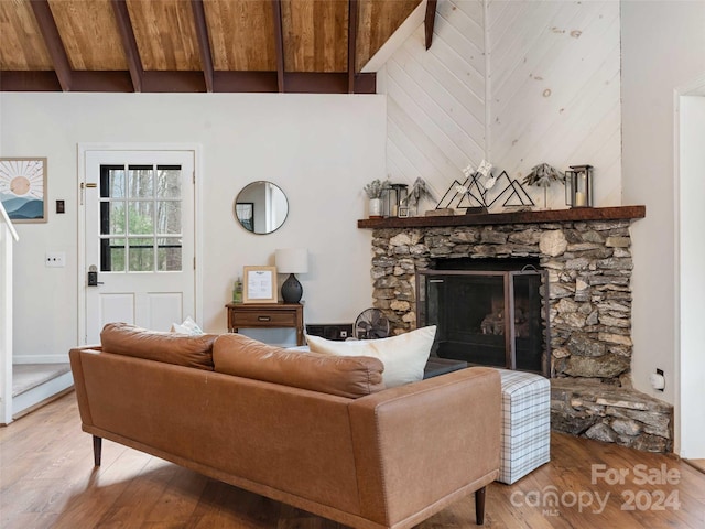 living room featuring beam ceiling, hardwood / wood-style flooring, high vaulted ceiling, and a stone fireplace