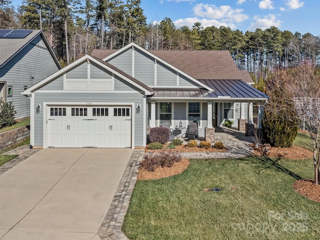 view of front of house featuring covered porch, a garage, and a front lawn