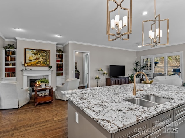 kitchen featuring light stone counters, sink, pendant lighting, a center island with sink, and dark hardwood / wood-style floors