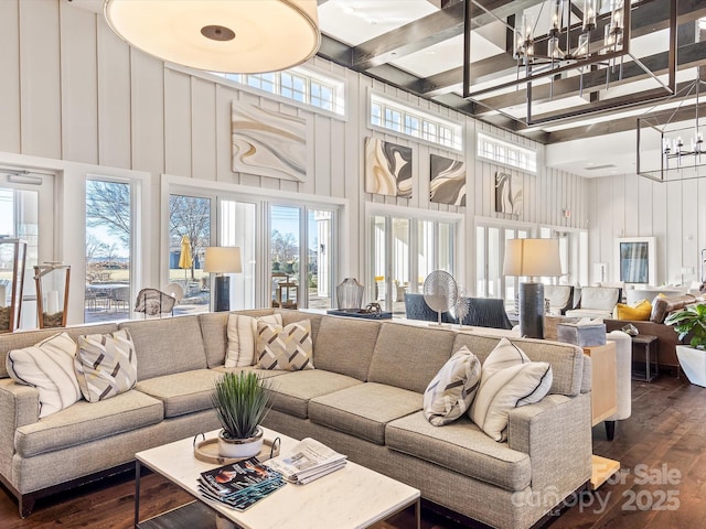 living room with beam ceiling, dark hardwood / wood-style flooring, a towering ceiling, and a chandelier