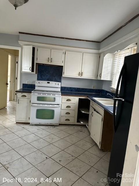 kitchen with black fridge, sink, white stove, white cabinetry, and light tile patterned flooring