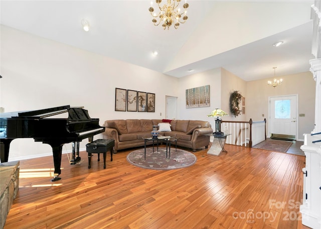 living room featuring high vaulted ceiling, a chandelier, and light hardwood / wood-style floors