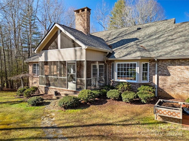 rear view of house with a sunroom and a yard