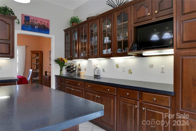 kitchen with backsplash, dark brown cabinetry, and light tile patterned floors