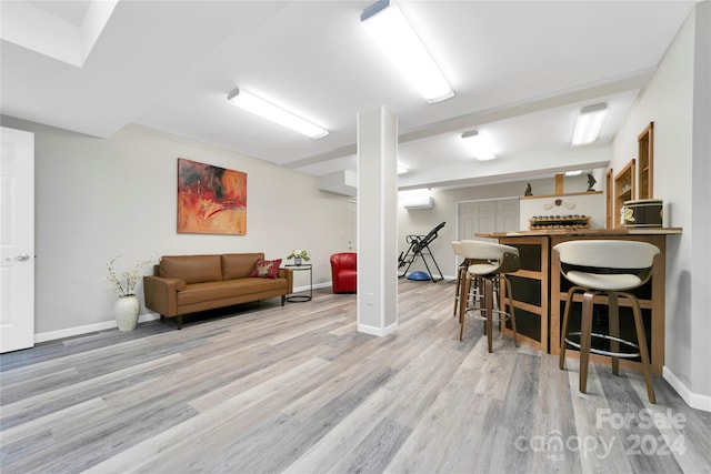 interior space with indoor bar, light hardwood / wood-style flooring, and a wall unit AC