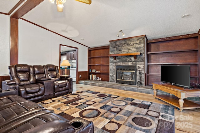 living room featuring wooden walls, a fireplace, a textured ceiling, and ornamental molding