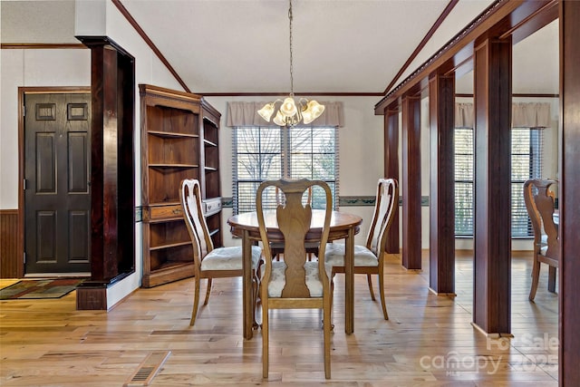 dining room with lofted ceiling, light hardwood / wood-style floors, crown molding, and a notable chandelier