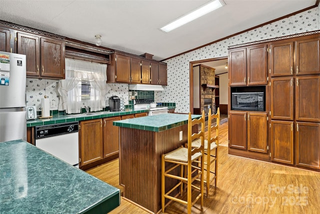 kitchen featuring a kitchen island, ornamental molding, black microwave, and vaulted ceiling