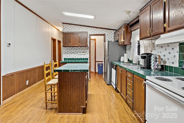 kitchen featuring ornamental molding, vaulted ceiling, dishwasher, a kitchen island, and a breakfast bar area