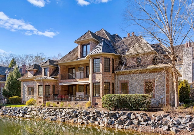 back of property with a water view and a balcony