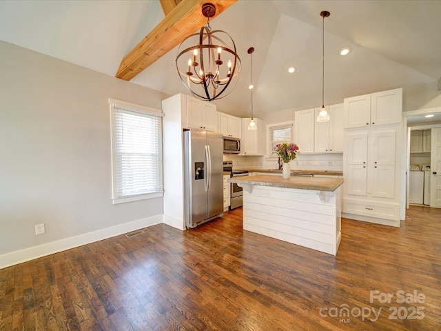 kitchen featuring white cabinets, appliances with stainless steel finishes, washer and clothes dryer, and pendant lighting