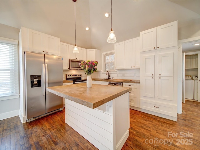 kitchen featuring white cabinetry, a center island, washing machine and dryer, backsplash, and appliances with stainless steel finishes