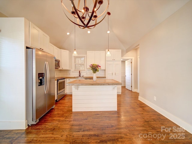 kitchen featuring backsplash, stainless steel appliances, an inviting chandelier, white cabinets, and a center island