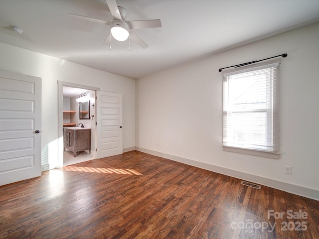 unfurnished bedroom with ensuite bathroom, ceiling fan, and dark wood-type flooring