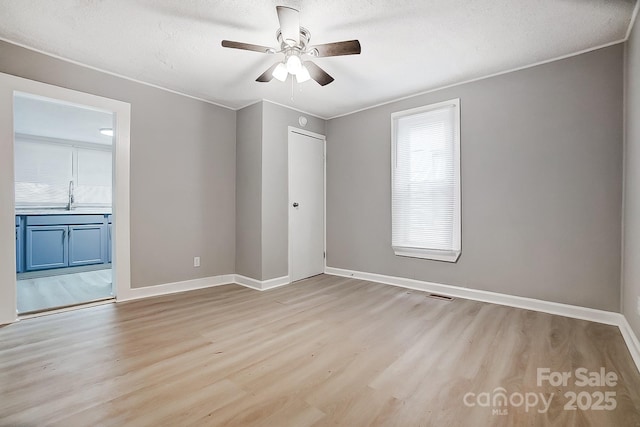 unfurnished room with light hardwood / wood-style flooring, ceiling fan, ornamental molding, and sink