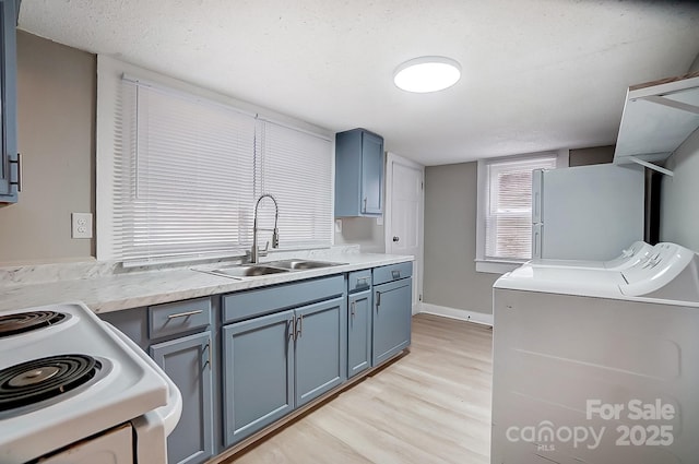 kitchen with white refrigerator, sink, range with electric stovetop, washing machine and dryer, and a textured ceiling