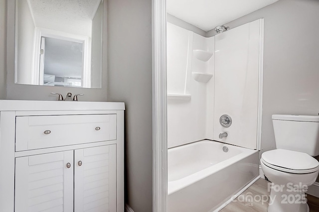 full bathroom featuring wood-type flooring, a textured ceiling,  shower combination, toilet, and vanity