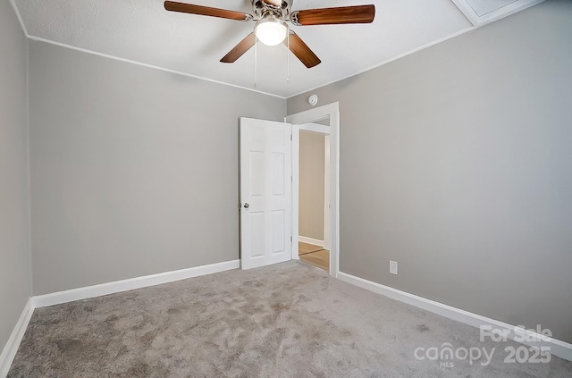 spare room with ceiling fan, crown molding, and light colored carpet