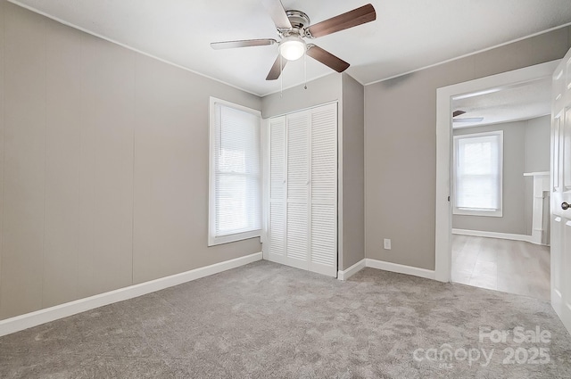 unfurnished bedroom featuring multiple windows, ceiling fan, a closet, and light colored carpet