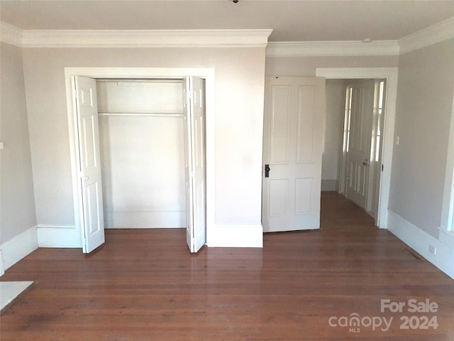 unfurnished bedroom featuring a closet, dark wood-type flooring, and ornamental molding