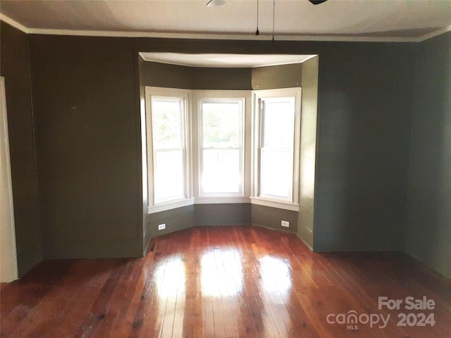 empty room with dark wood-type flooring and ornamental molding