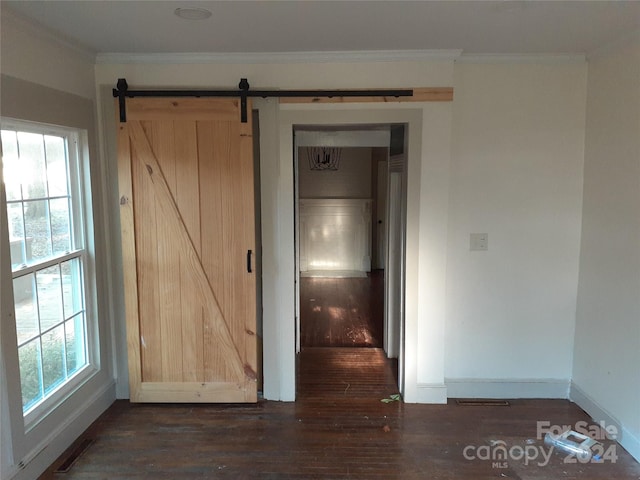 interior space featuring a barn door, ornamental molding, and dark wood-type flooring