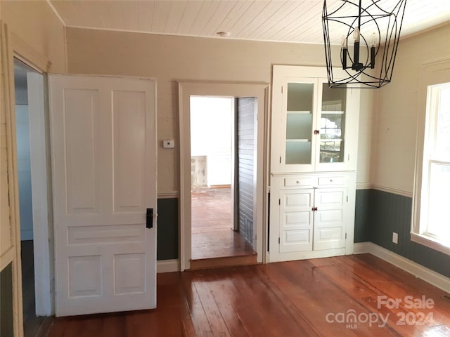 unfurnished dining area featuring dark hardwood / wood-style flooring and an inviting chandelier