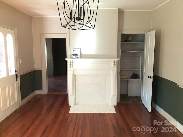 unfurnished dining area featuring dark wood-type flooring and an inviting chandelier