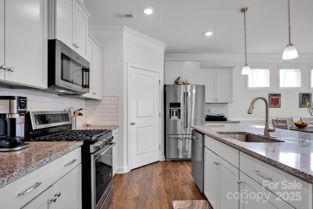 kitchen with white cabinets, appliances with stainless steel finishes, light stone counters, and sink