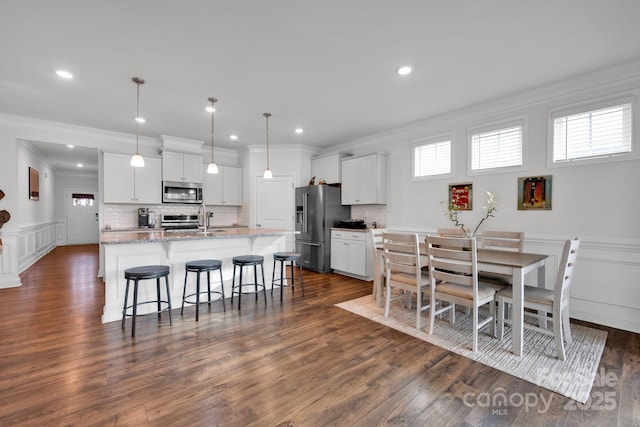 dining area with dark hardwood / wood-style floors, crown molding, and sink