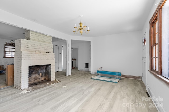 unfurnished living room featuring a fireplace, light wood-type flooring, and a chandelier