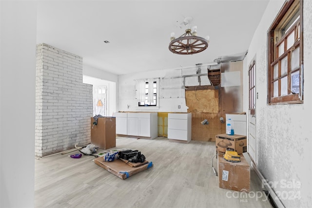 interior space with light hardwood / wood-style floors and brick wall