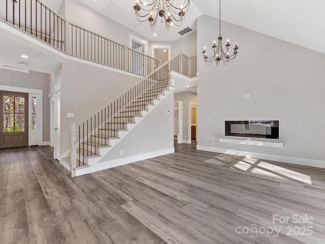 unfurnished living room with hardwood / wood-style floors, a high ceiling, and an inviting chandelier