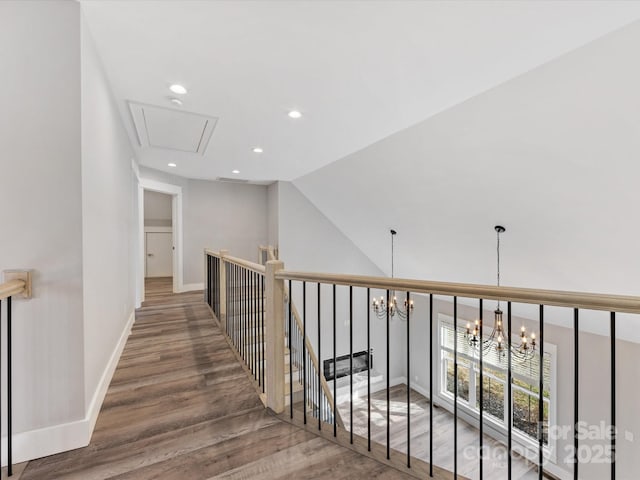 hallway with dark hardwood / wood-style flooring, lofted ceiling, and a notable chandelier