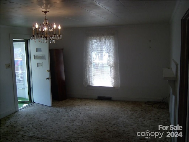 carpeted empty room with a notable chandelier