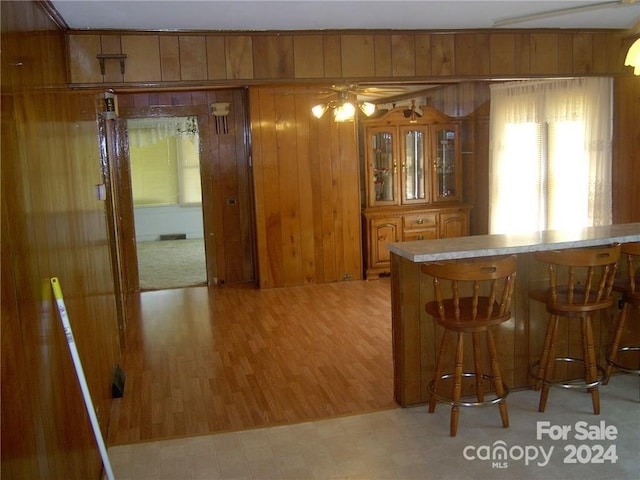 kitchen featuring ceiling fan, a breakfast bar area, and wood walls