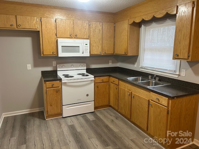 kitchen featuring a textured ceiling, dark hardwood / wood-style floors, white appliances, and sink