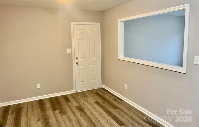 empty room with wood-type flooring and a textured ceiling