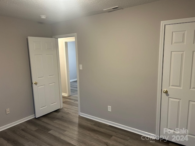 unfurnished room featuring dark wood-type flooring and a textured ceiling