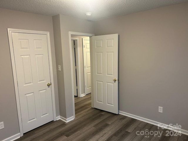 unfurnished bedroom with a textured ceiling and dark wood-type flooring