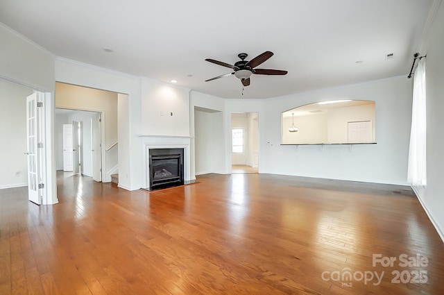 unfurnished living room with hardwood / wood-style floors, ceiling fan, and ornamental molding