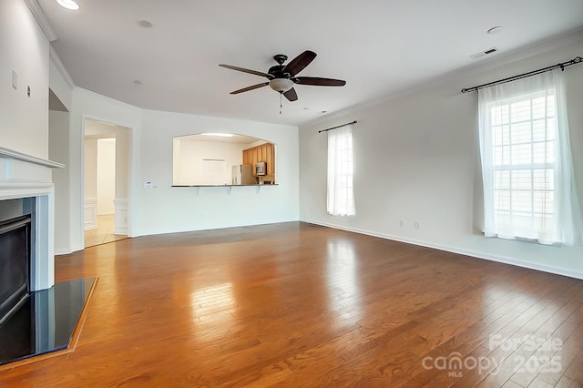 unfurnished living room featuring hardwood / wood-style flooring, ceiling fan, and crown molding