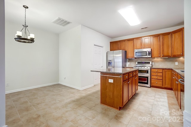 kitchen with hanging light fixtures, stainless steel appliances, an inviting chandelier, decorative backsplash, and a kitchen island