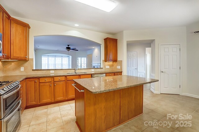 kitchen featuring light tile patterned flooring, sink, ceiling fan, appliances with stainless steel finishes, and a kitchen island