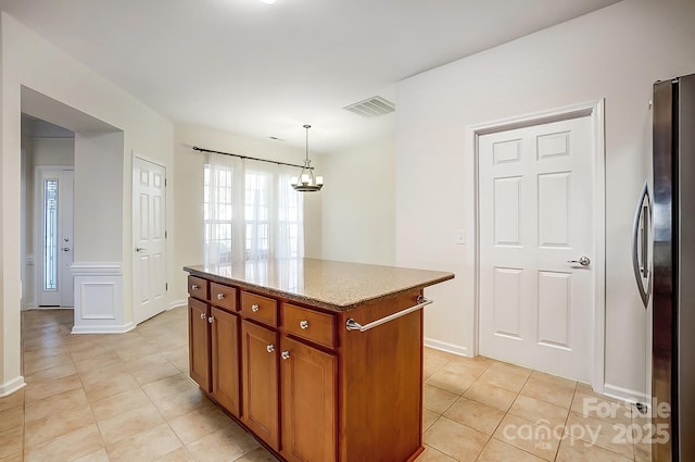 kitchen featuring a center island, hanging light fixtures, light tile patterned floors, a notable chandelier, and stainless steel refrigerator