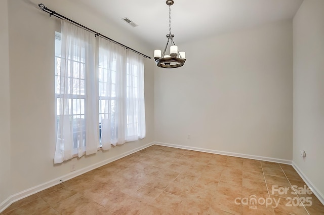 tiled spare room featuring a notable chandelier