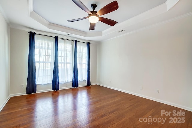 spare room featuring ceiling fan, a raised ceiling, ornamental molding, and dark wood-type flooring