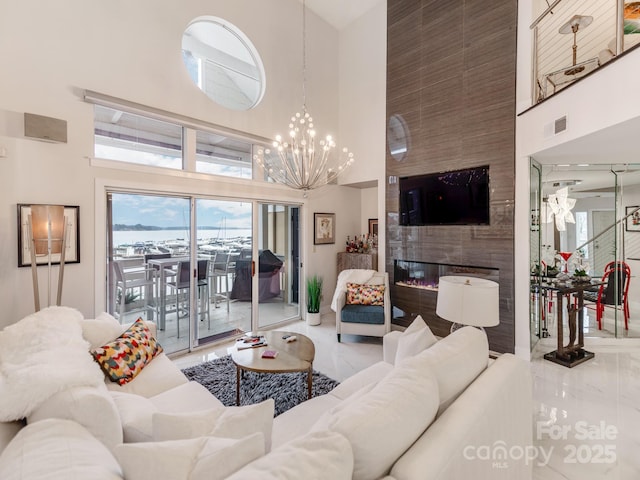 living room featuring a high ceiling, a notable chandelier, and a fireplace